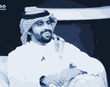 a man wearing a head scarf is smiling in front of a sign that says channels on it