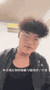 a man wearing glasses and a black jacket with the letter u on it