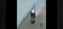 a spray can is sitting on the floor next to a wall with smoke coming out of it .