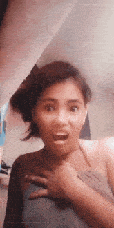 a woman is making a funny face with her mouth open and her hands on her chest .