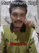 a man wearing headphones and a green shirt with the words mari minum kopi