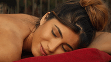 a woman with her eyes closed is laying on a red blanket