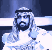 a man with a beard is wearing a white shirt and a black and white head scarf