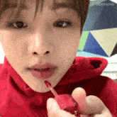 a close up of a person applying lipstick on their lips .