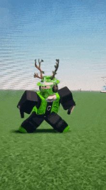 a person in a green and black outfit with antlers on their head is standing in the grass .