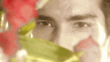 a close up of a man 's face with flowers behind it