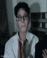 a blurry picture of a man wearing glasses and a white shirt