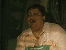 a woman in a pink shirt is laughing and holding a green cloth