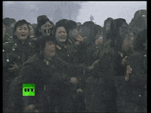 a group of people standing in the rain with a green rtn logo on the bottom