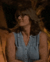 a woman wearing glasses and a blue shirt is sitting on a chair