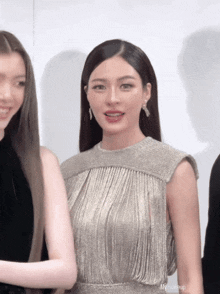 a woman wearing a silver dress with fringe is standing next to another woman