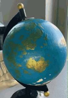 a blue globe with gold spots on the earth