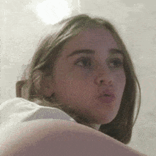 a close up of a woman 's face with a white shirt on