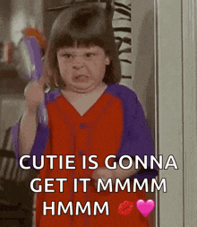 a little girl is holding a toothbrush and saying cutie is gonna get it mmmm hmm