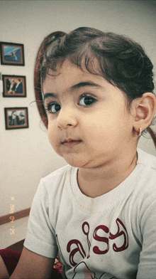 a little girl wearing a t-shirt that says aissy
