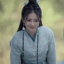 a woman with braids and pearls in her hair is wearing a blue shirt