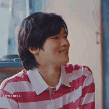 a young man wearing a pink and white striped shirt with little bear written on it