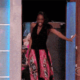 a woman in a pink and black dress is standing in a doorway with her arms outstretched