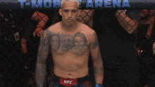 a shirtless ufc fighter stands in front of a t-mobile arena banner