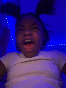 a little girl making a funny face in front of a blue light