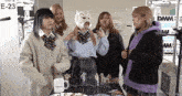 a group of girls are standing around a table with a sign that says e-23