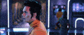 a man in an orange jacket stands in a room
