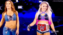 a couple of women standing next to each other on a stage . one of the women is wearing a pink belt .