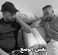 two men are sitting on a couch and one of them is wearing a beverly hills polo club shirt