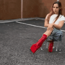 a woman is sitting on a chair with her legs crossed and wearing red boots .