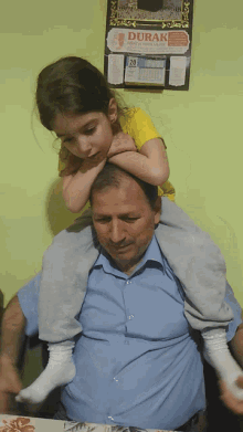 a man is carrying a little girl on his shoulders in front of a wall calendar that says durak