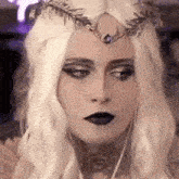 a close up of a woman wearing a wig and a crown .