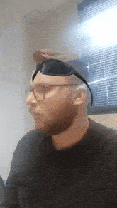a man wearing glasses and sunglasses looks to his left
