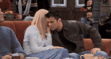 a man and a woman are sitting on a couch with a cup of coffee in front of them