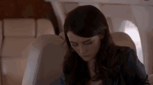 a woman is sitting in the back seat of a plane looking down .