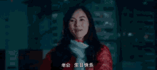 a woman in a red jacket and scarf is standing in front of a building and smiling .