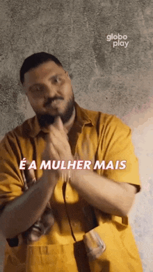 a man with a beard is wearing a yellow shirt and making a funny face .