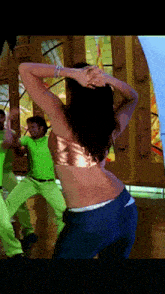 a woman in a crop top is dancing with a man in a green shirt