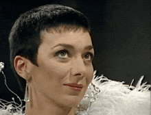 a close up of a woman 's face with a white feather covering her shoulder