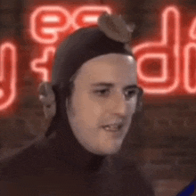 a man in a wet suit is standing in front of a neon sign and smiling .
