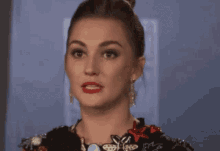 a woman with a surprised look on her face is wearing a dress and earrings .
