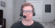 a man wearing glasses and a headset with a microphone is sitting in a living room .