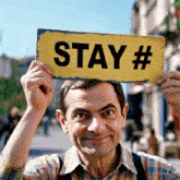 a man holding a sign that says stay #