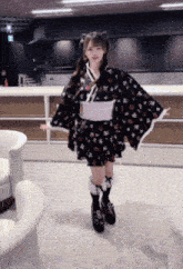 a girl in a kimono stands in a room with chairs