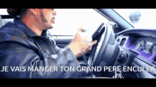 a man driving a car with the words " je vais manger ton grand pere encule " on the screen