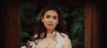 a woman in a white dress is making a funny face while standing in front of a window .