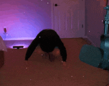 a person is doing a handstand in a room with purple lights