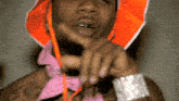 a close up of a man wearing an orange hat and a pink scarf