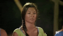a woman in a green shirt is making a face with her eyes closed .