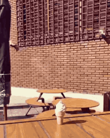 an ice cream cone is sitting on a wooden table in front of a brick building .