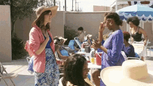 a group of women are standing around a pool with umbrellas .